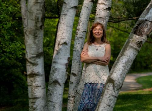 Professor Elena Lioubimtseva stands in a wooded area in a grouping of birch trees with white bark.